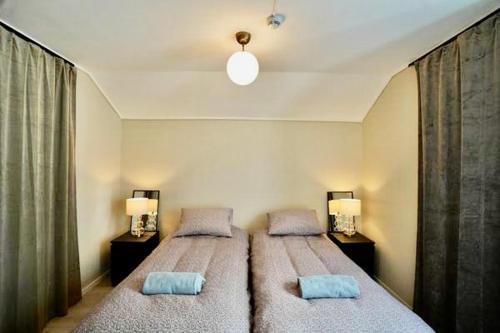 波什格伦Sentralt i rolig bygård, med heis, egen, veranda & 85" Smart TV的一间卧室配有两张床、两盏灯和窗帘