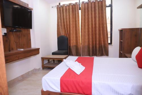瓜廖尔TRP Rama Inn的酒店客房设有一张带电视和窗户的床。