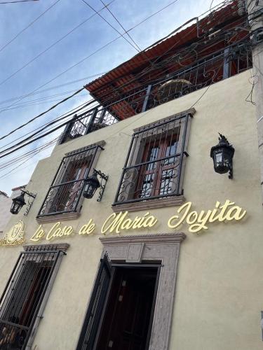 阿瓜斯卡连特斯Hotel La Casa de María Joyita的建筑一侧的标志,带有窗户