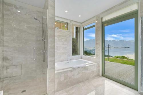皇后镇Ruby's Fernhill Vista的一间带浴缸和淋浴的浴室,并设有一个窗户