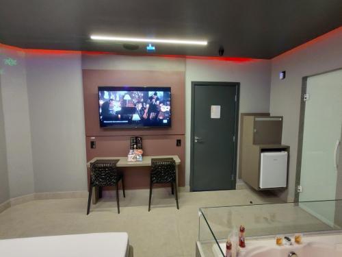 索罗卡巴Prestige Motel 2的一间配有电视的墙壁,配有桌椅