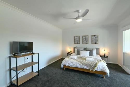 达博Tamworth Retreat - Sleek & Stylish, Sleeps 5的一间卧室配有一张床和一台平面电视