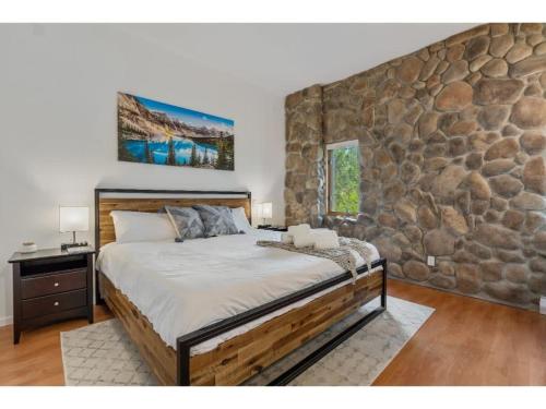 因弗米尔Chardonnay Chalet I Fireplace I Mountain View I TV的一间卧室设有一张带石墙的大床