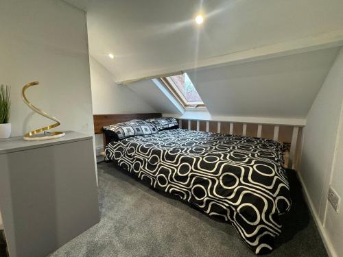 卢顿Duplex Studio 3 minute drive from Luton airport的一间卧室配有一张带黑白色棉被的床