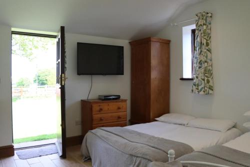 DilhorneMalthouse Farm Cottage Studio的一间卧室配有两张床和一台平面电视