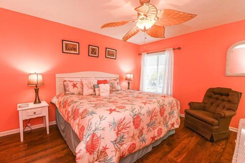 默特尔比奇Island Breeze Pet Friendly Bungalow w Pool的一间卧室拥有橙色的墙壁,配有一张床和椅子