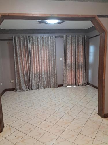 金贾ZET HOLDINGS的一间空房间,配有窗帘,铺有瓷砖地板