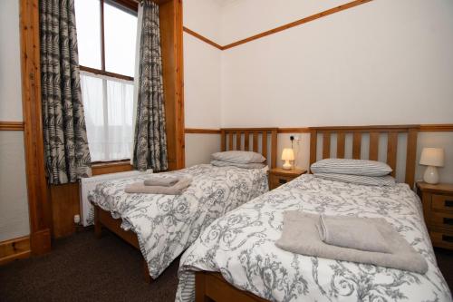 勒威克Alder Lodge Guest House的带窗户的客房内设有两张单人床。