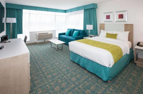 兰利海岸酒店&会议中心的酒店客房设有一张大床和一张蓝色的沙发。