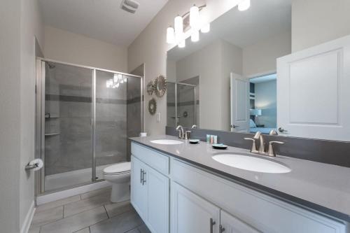 基西米Charming 9BR Villa w Theme & Game Rooms by Disney的一间带两个盥洗盆、淋浴和卫生间的浴室