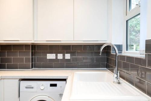 伦敦Lovely 2BR house in Norwood Junction London的白色的厨房配有水槽和洗碗机