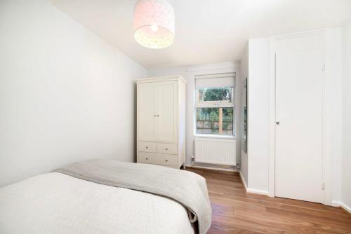 伦敦Charming 1BR flat with patio perfect for couples的白色的卧室设有床和窗户