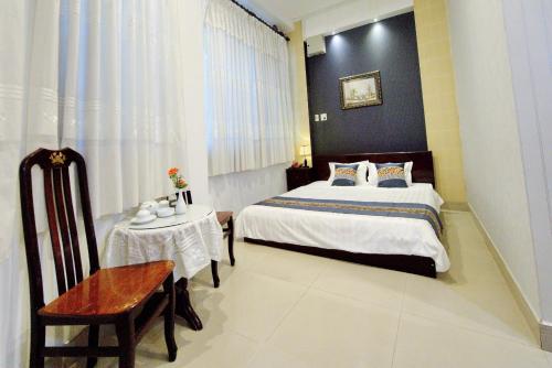 朱笃Hotel Hải Châu的一间卧室配有一张床、一把椅子和一张桌子