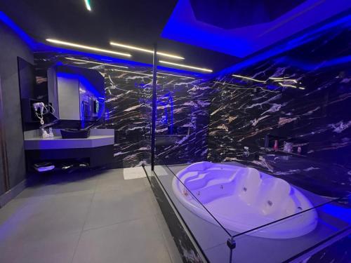索罗卡巴Prestige Motel 4的一间带浴缸的浴室,位于蓝色灯光的房间