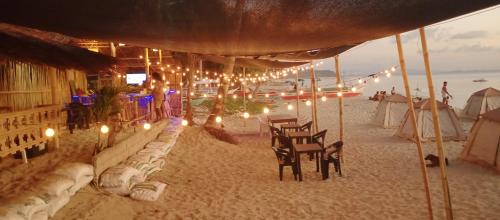 圣维森特Amwani Sunset Colours Camping Site的沙滩上带椅子和灯的海滩