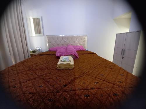 SukoharjoBELLA NINE EXCLUSIVE HOMESTAY的一间卧室配有一张带毯子和紫色枕头的床