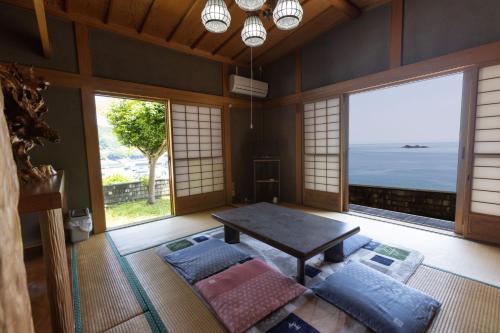 熊野市Oninosanpomichi的客厅设有桌子和大窗户