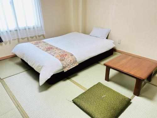 会津若松グリーンホテル会津的一间卧室配有一张床和一张木桌