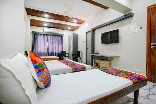 纳西克FabHotel Priya Lodging, near Ojhar Airport的酒店客房设有两张床和电视。