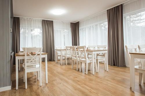 维斯瓦Willa Klonowa的一间设有白色桌椅和窗户的用餐室