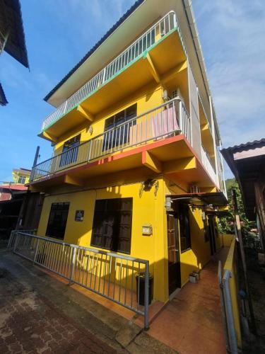 Kampong Pasir HantuJV Inn Perhentian的黄色的建筑,旁边设有阳台