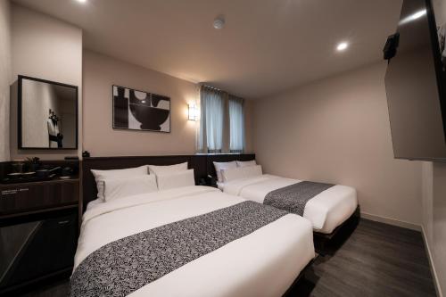 坡州市AANK Ryokan Hotel Paju的酒店客房设有两张床和电视。