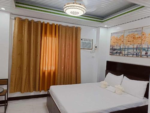 卢纳将军城KMJ SUITES的一间卧室配有一张带橙色窗帘的床