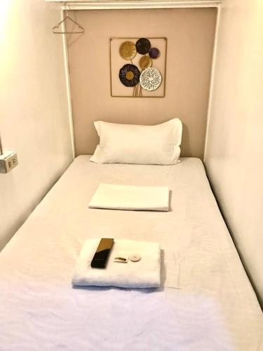 马尼拉Budget Transient Capsule Room Mirasol Near BGC的一张带白色毯子的床和一本书