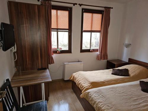 科普里夫什迪察Емили Фемили Хаус的一间卧室设有两张床、一台电视和两个窗户。