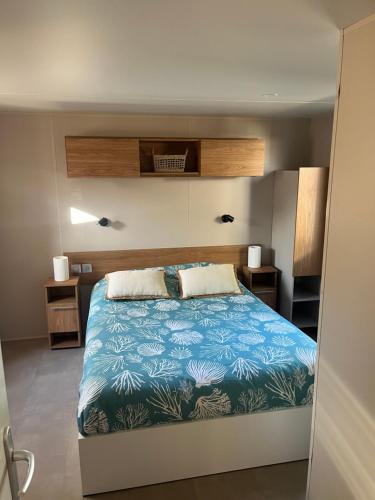 雷日卡普费雷Mobil home climatisé au calme et proche des activités LEGE CAP FERRET的一间卧室配有一张带蓝色毯子的大床
