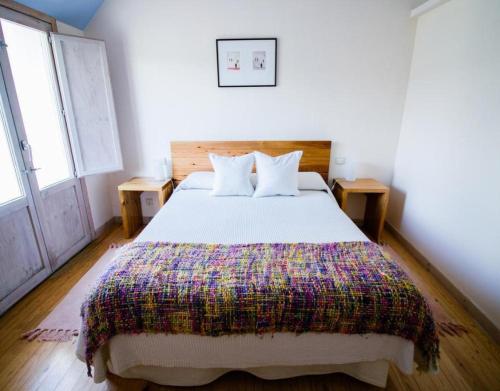 皇后山Casa Rural Marialba的一间卧室配有一张大床和色彩缤纷的毯子