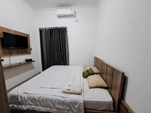井里汶OYO 93870 Damai Guest House Cirebon的配有电视和四柱床的客房内的一张床位