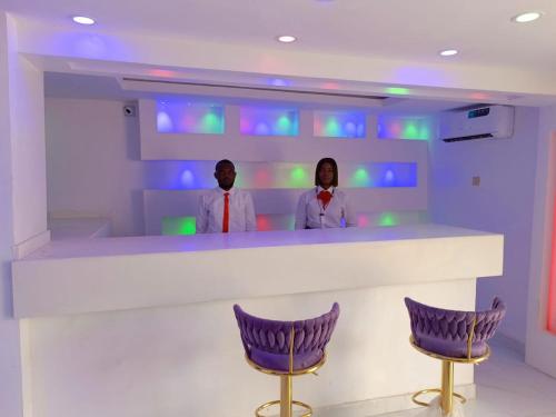 伊巴丹Global Signature Hotel and Resort的两人站在带紫色椅子的酒吧