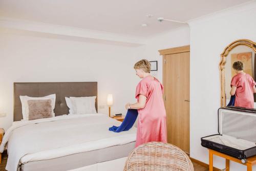韦斯特洛吉尔特酒店的粉色的女人正在打扫一张床