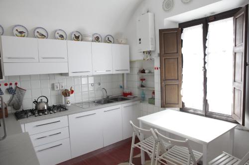 卡尔奇Villa Coli的厨房配有白色橱柜和桌椅