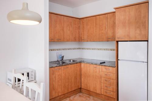 埃斯塔蒂特Apartamentos Torrevella的厨房配有木制橱柜和白色冰箱。
