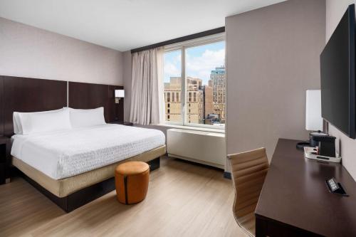 纽约时代广场中心汉普顿酒店的配有一张床、一张书桌和一扇窗户的酒店客房