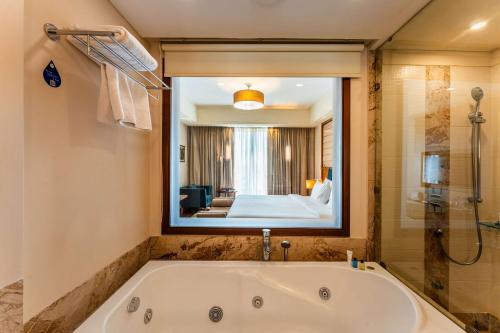 印多尔印多尔丽笙酒店的带浴缸的浴室和大镜子