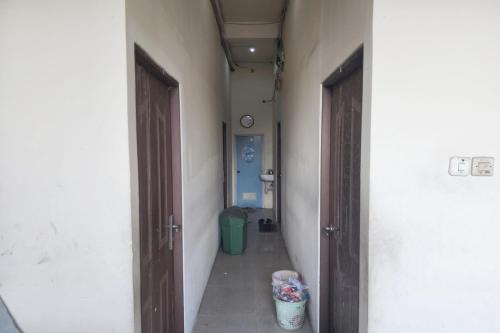 泗水OYO 93863 Dv Homestay Syariah Genteng的空的走廊,有两扇门,垃圾桶