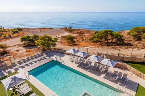 比利亚霍约萨Blue Line Apartment Hotel的享有带椅子的游泳池和大海的顶部景致