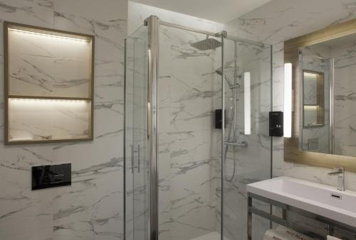 马德里丘埃卡小宫殿酒店的一间带玻璃淋浴和水槽的浴室