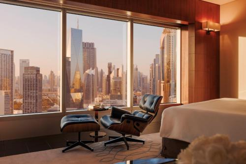 迪拜Jumeirah Emirates Towers Dubai的一间卧室配有一张床和两把椅子,并设有一个大窗户