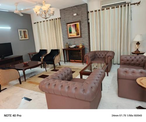 伊斯兰堡Palladium Executive的客厅配有真皮沙发和电视
