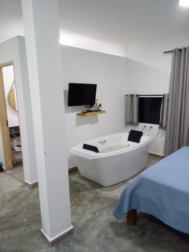 圣托梅-达斯莱特拉斯Chales Paraíso STL的带电视的客房内的白色浴缸