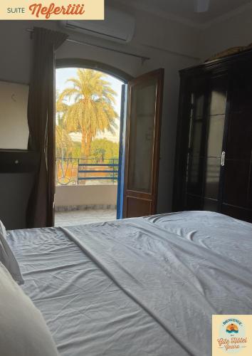卢克索Gîte Hôtel Gezira Louxor 2的一间卧室设有一张床,享有棕榈树的景色