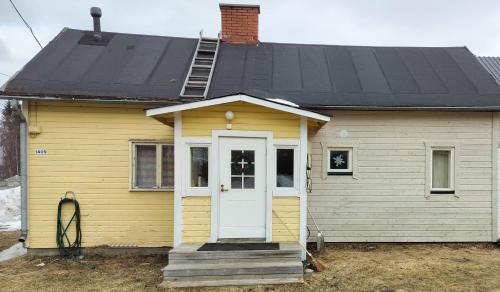 托尔尼奥Riverside Restplace的黄色的房子,有白色的门和黑色的屋顶