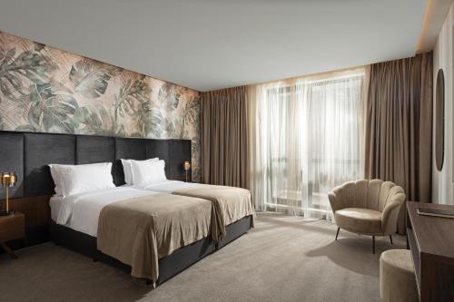 帕维尔巴尼亚Grand Resort Pavel Banya Medical and SPA EpiCentrum的一间卧室配有一张大床和一把椅子