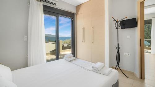尼基亚娜Agni Suites的卧室设有白色的床和大窗户