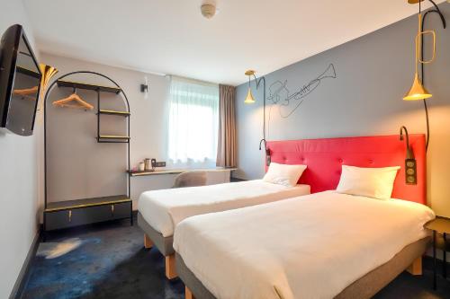马恩河畔博纳伊克雷泰伊马恩河畔波涅基里亚德酒店的酒店客房设有两张床和红色床头板