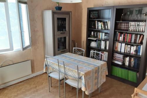 圣弗卢尔Grand T1 meublé的一间带桌椅和书架的用餐室
